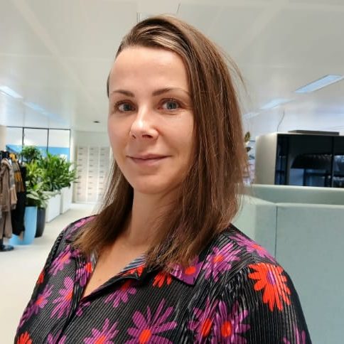 Vrouw met lange, bruin haar en een lichte huid glimlacht in natuurlijk licht.